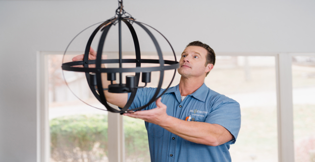 Electrician hangs a new light fixture in a home.