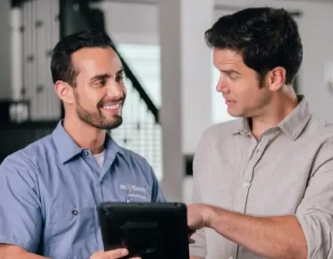 Mr. Electric technician showing tablet to customer.