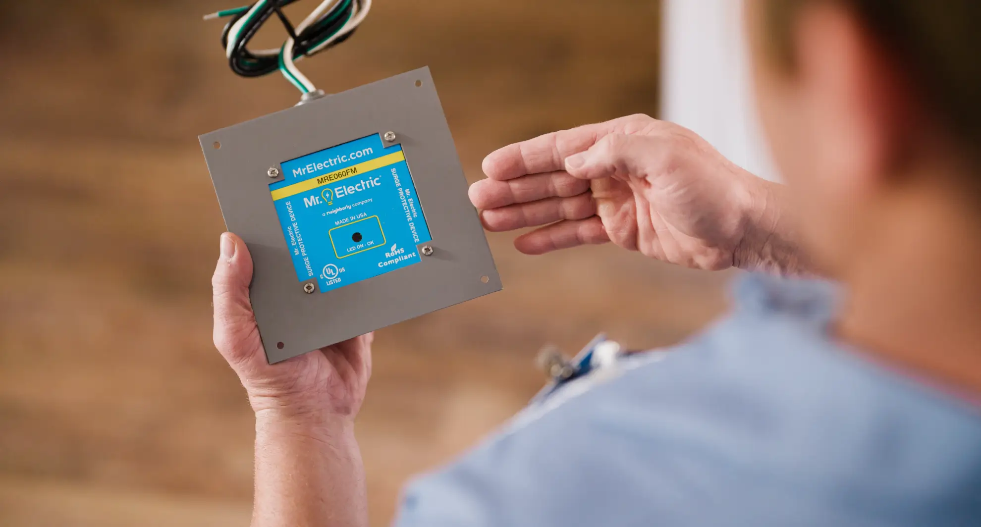 Close-up of electrician holding whole house surge protector device